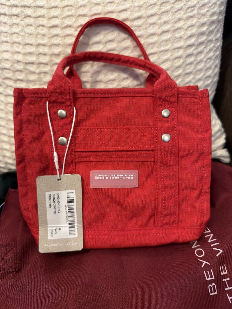 Beyond The Vines Crunch Carryall 0.5 Cherry Red (Category: Tote Bags) located in Makati City. Submitted by ANewHome (Listing ID 1465894885, Image 1). Description: - Brand: Beyond The Vines - Style: Crunch Carryall (0.5 - Extra Small) - Color: Bright Cherry Red with contrast blue interior - Material: Durable, water-resistant nylon with branded rubber front patch - Features: Double top handles and adjustable long strap (can do crossbody) -Inclusion