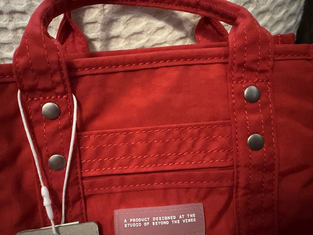 Beyond The Vines Crunch Carryall 0.5 Cherry Red (Category: Tote Bags) located in Makati City. Submitted by ANewHome (Listing ID 1465894885, Image 2). Description: - Brand: Beyond The Vines - Style: Crunch Carryall (0.5 - Extra Small) - Color: Bright Cherry Red with contrast blue interior - Material: Durable, water-resistant nylon with branded rubber front patch - Features: Double top handles and adjustable long strap (can do crossbody) -Inclusion