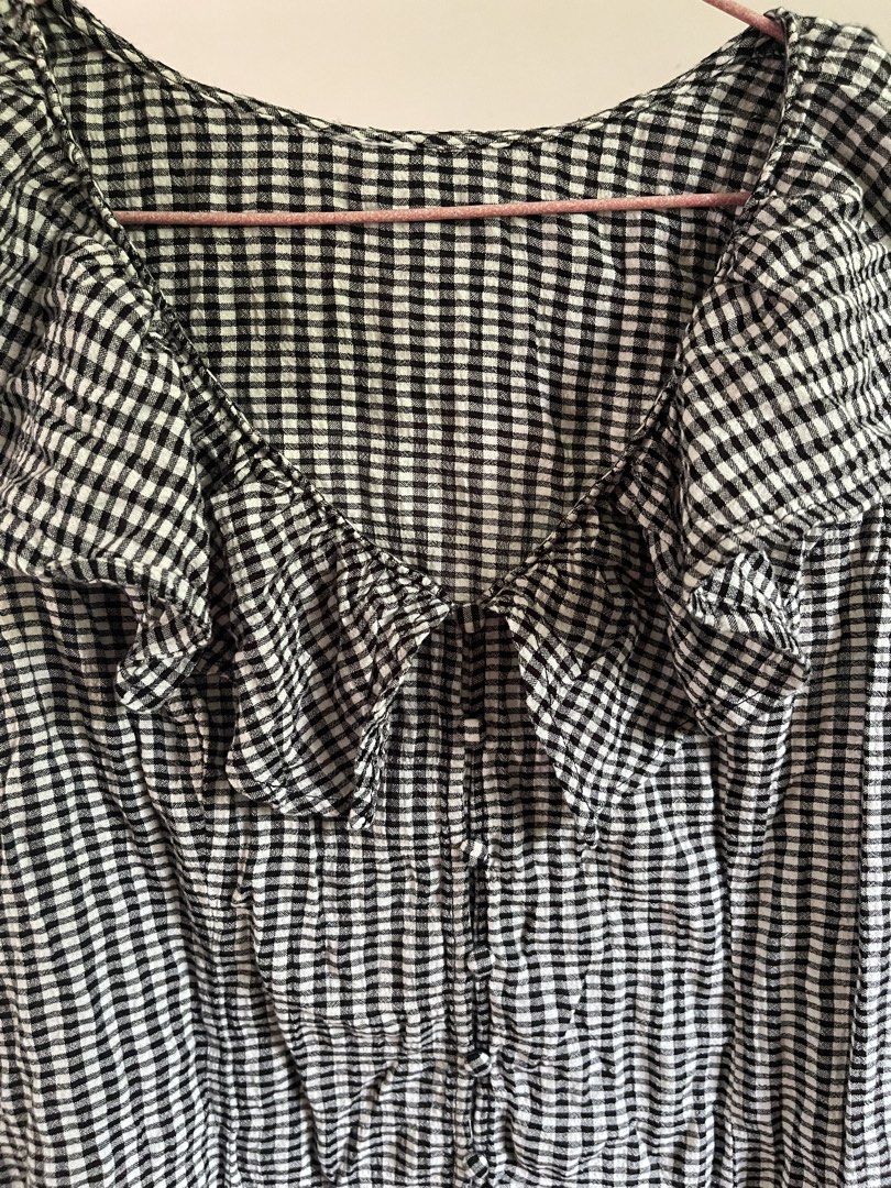 Black and White Gingham Ruffle Blouse (Category: Blouses) located in Baybay. Submitted by shikita27906 (Listing ID 1465847976, Image 2). Description: - Pattern: Classic black and white gingham - Design: Wide ruffled collar - Closure: Front button-up with small dark buttons - Material: Lightweight, textured crinkled fabric.
