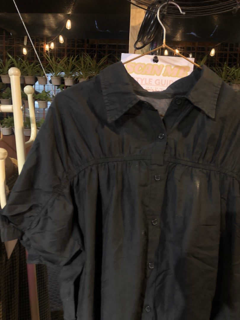 Black button-down short sleeve blouse top (Category: Blouses) located in Cauayan City . Submitted by wholly.craaaft (Listing ID 1465874722, Image 2). Description: - Color: Black - Style: Short sleeve button-down with a classic collar - Fit: Loose fit, lightweight, and breathable - Design: Elegant gathered detail across the chest and standard front button closure - Versatility: Perfect for pairing with skirts or trousers for casual outings.