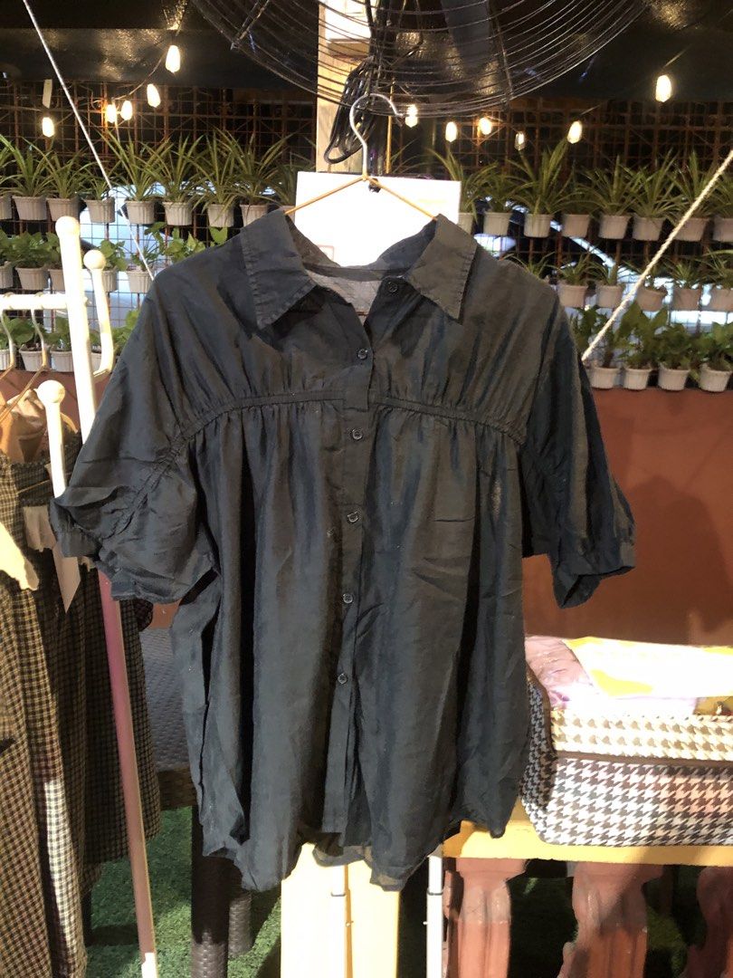 Black button-down short sleeve blouse top (Category: Blouses) located in Cauayan City . Submitted by wholly.craaaft (Listing ID 1465874722, Image 1). Description: - Color: Black - Style: Short sleeve button-down with a classic collar - Fit: Loose fit, lightweight, and breathable - Design: Elegant gathered detail across the chest and standard front button closure - Versatility: Perfect for pairing with skirts or trousers for casual outings.