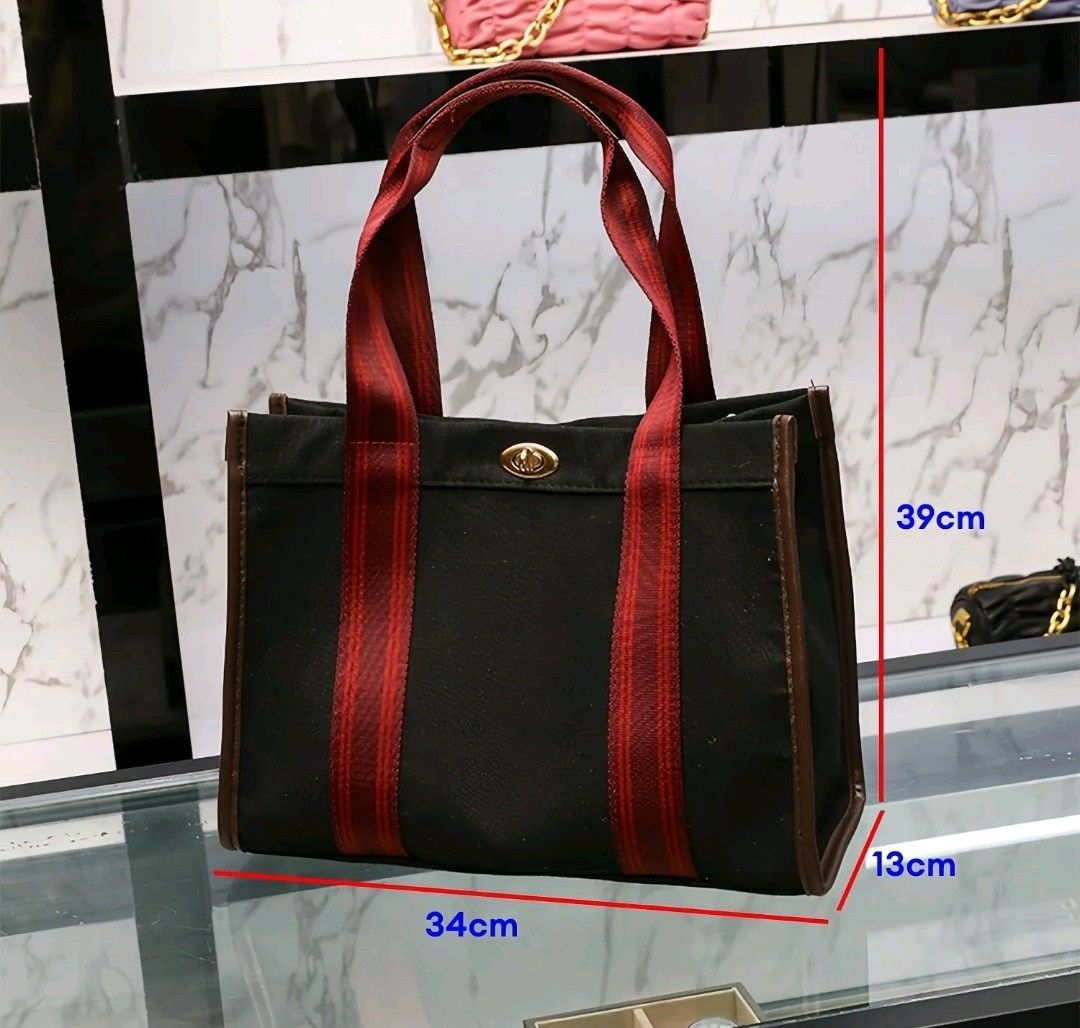 Black Canvas Tote Bag with Red Straps (Category: Tote Bags) located in Quezon City. Submitted by mhiemime (Listing ID 1465797866, Image 3). Description: - Color: Black canvas with striking red striped handles and dark brown trim - Hardware: Elegant gold-tone twist-lock clasp on the front - Dimensions: 34cm (L) x 13cm (W) x 39cm (H) - Features: Spacious interior for daily essentials, work, or school; solid structure that holds its shape well - Str
