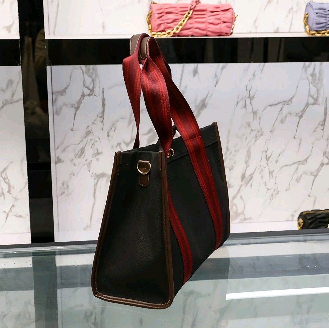 Black Canvas Tote Bag with Red Straps (Category: Tote Bags) located in Quezon City. Submitted by mhiemime (Listing ID 1465797866, Image 2). Description: - Color: Black canvas with striking red striped handles and dark brown trim - Hardware: Elegant gold-tone twist-lock clasp on the front - Dimensions: 34cm (L) x 13cm (W) x 39cm (H) - Features: Spacious interior for daily essentials, work, or school; solid structure that holds its shape well - Str