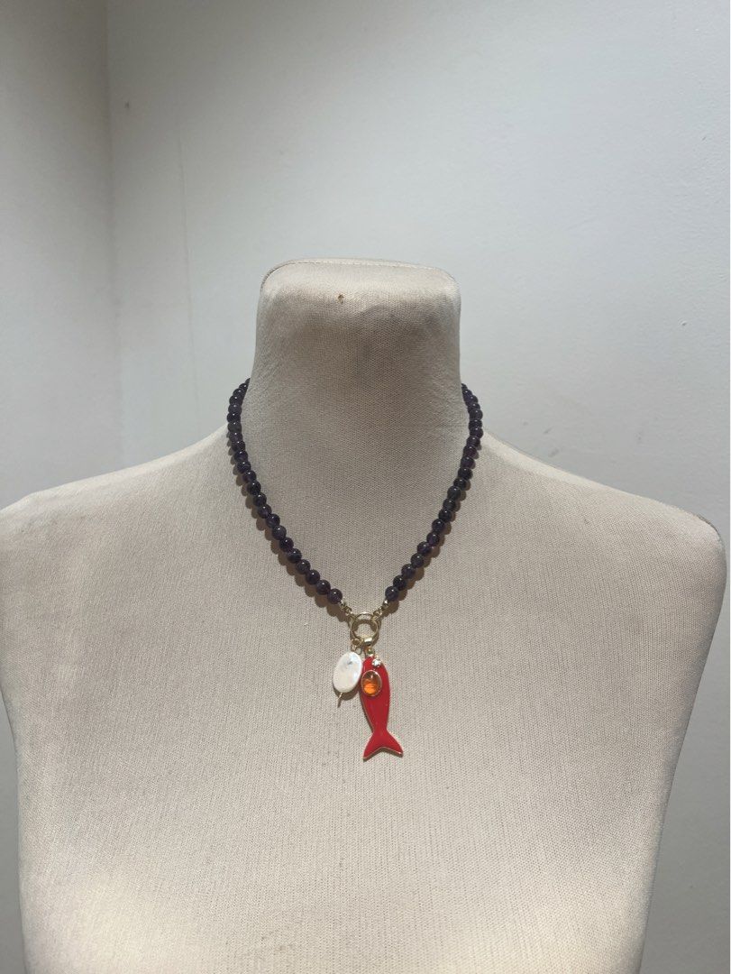 Black garnet Necklace with Red Fish Charm (Category: Necklaces) located in Quezon City. Submitted by iminquezoncity (Listing ID 1465871305, Image 1). Description: - Dark beaded necklace that sits comfortably at the collarbone - Features a secure gold clasp ring - Attached charms include an oval white pearl-like piece and a vibrant red enamel fish - Fish charm accented with a sparkling orange stone - Fun and unique statement accessory perfect for 