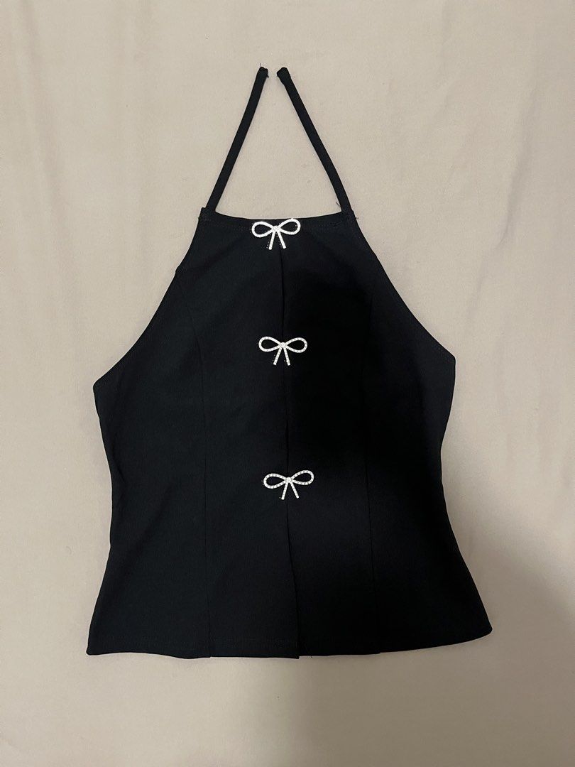 Black halter top ribbon (Category: Sleeveless) located in Marikina City. Submitted by maicsg_ (Listing ID 1465772869, Image 1). Description: - Color: Black - Style: Halter top, backless with thin straps - Details: Three rhinestone bows along the front slit - Fit: Fitted cut - Condition: Excellent (worn once for photos only, clean and ready to wear) - Styling tip: Pairs easily with denim shorts or skirts.