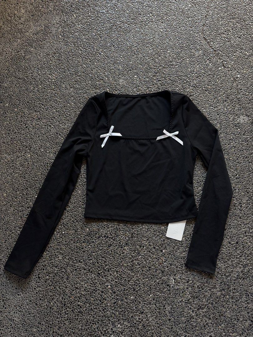 Black Long Sleeve Crop Top with White Bows (Category: Longsleeves) located in San Fernando. Submitted by gigikyla (Listing ID 1465923739, Image 1). Description: - Condition: Brand new with original tag attached (never worn) - Design: Black long sleeve top with a trendy square neckline and cropped fit - Details: Features two small white bows near the chest area - Material: Smooth and stretchy fabric for a comfortable fit - Styling: Great for casua