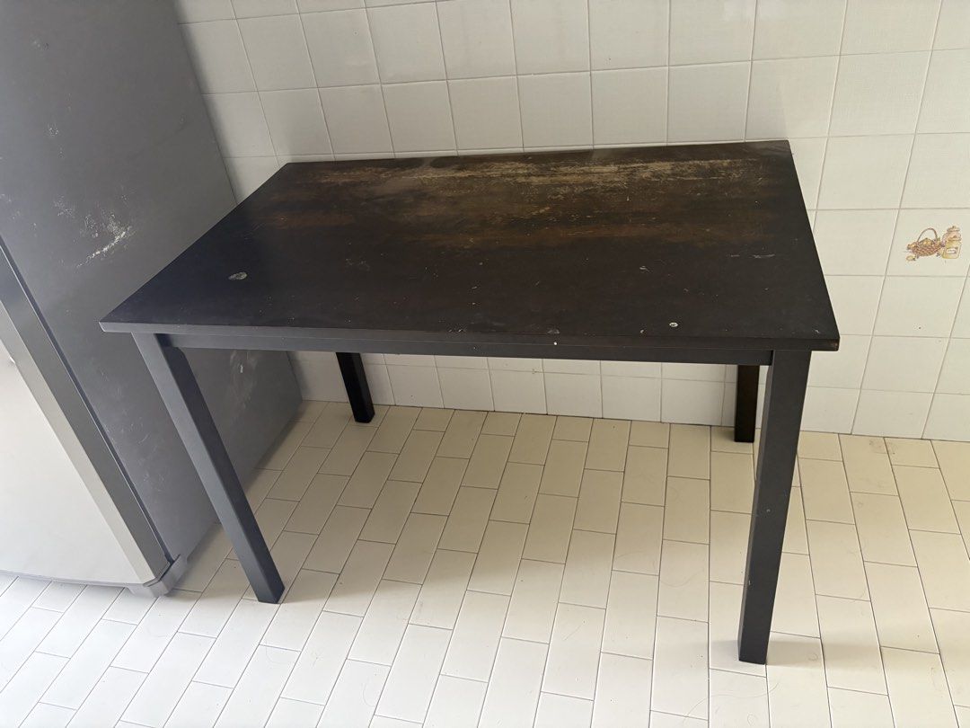 Black rectangular study dining table desk (Category: Tables & Sets) located in Singapore. Submitted by nadzeet9191 (Listing ID 1465916883, Image 1). Description: - Color: Black - Shape: Rectangular - Material: Sturdy metal legs with a heavily used surface - Condition: Shows significant wear, scuffs, and fading; perfect for a garage, workspace, or craft room - Capacity: Standard height, comfortably seats 4 - Maintenance: Needs a quick wipe down or