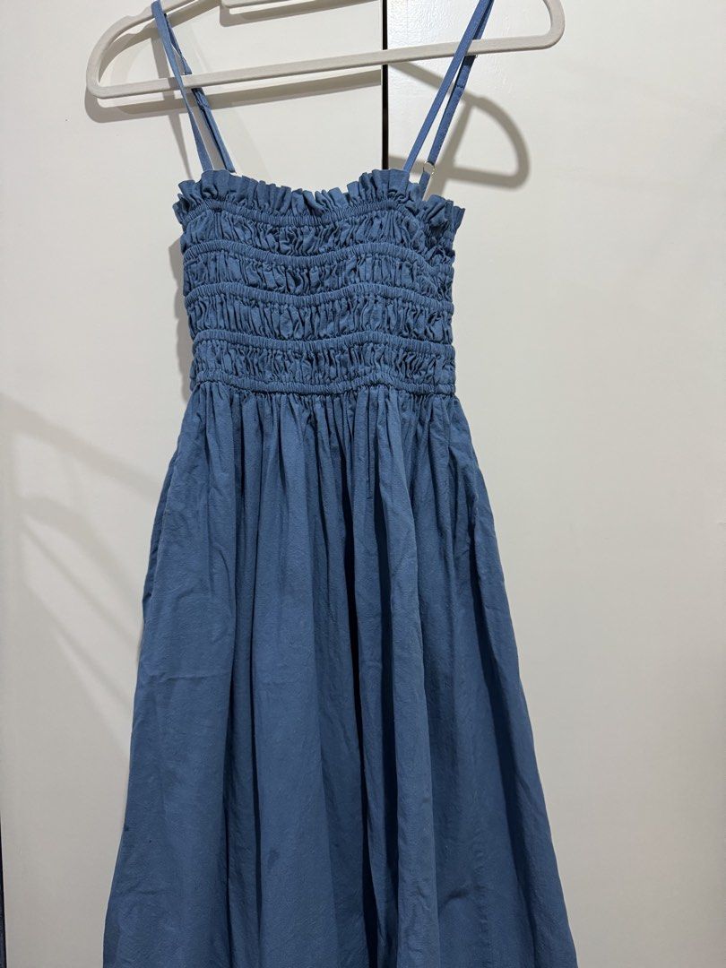 Blue Smocked Midi Dress with Adjustable Straps (Category: Dresses) located in Manila. Submitted by carmela_andd (Listing ID 1465904773, Image 1). Description: - Color: Dusty Blue - Length: Midi - Bodice: Heavily smocked with a ruffled neckline - Straps: Thin, adjustable with gold-tone hardware - Hem: Flowy with a subtle bubble bottom tier - Fabric: Lightweight and breathable - Style: Easy pull-on, perfect for casual days and warm weather.