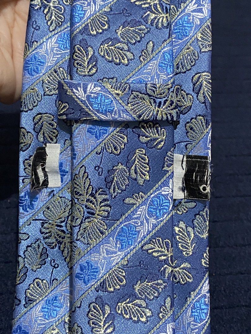 Blue striped floral patterned necktie 100% polyester (Category: Ties) located in Manila. Submitted by resi.diaz (Listing ID 1465893155, Image 3). Description: - Color: Blue with diagonal stripes and leaf floral pattern - Material: 100% polyester - Width: Standard blade - Care: Dry clean only (fabric care tag attached) - Origin: Made in China.