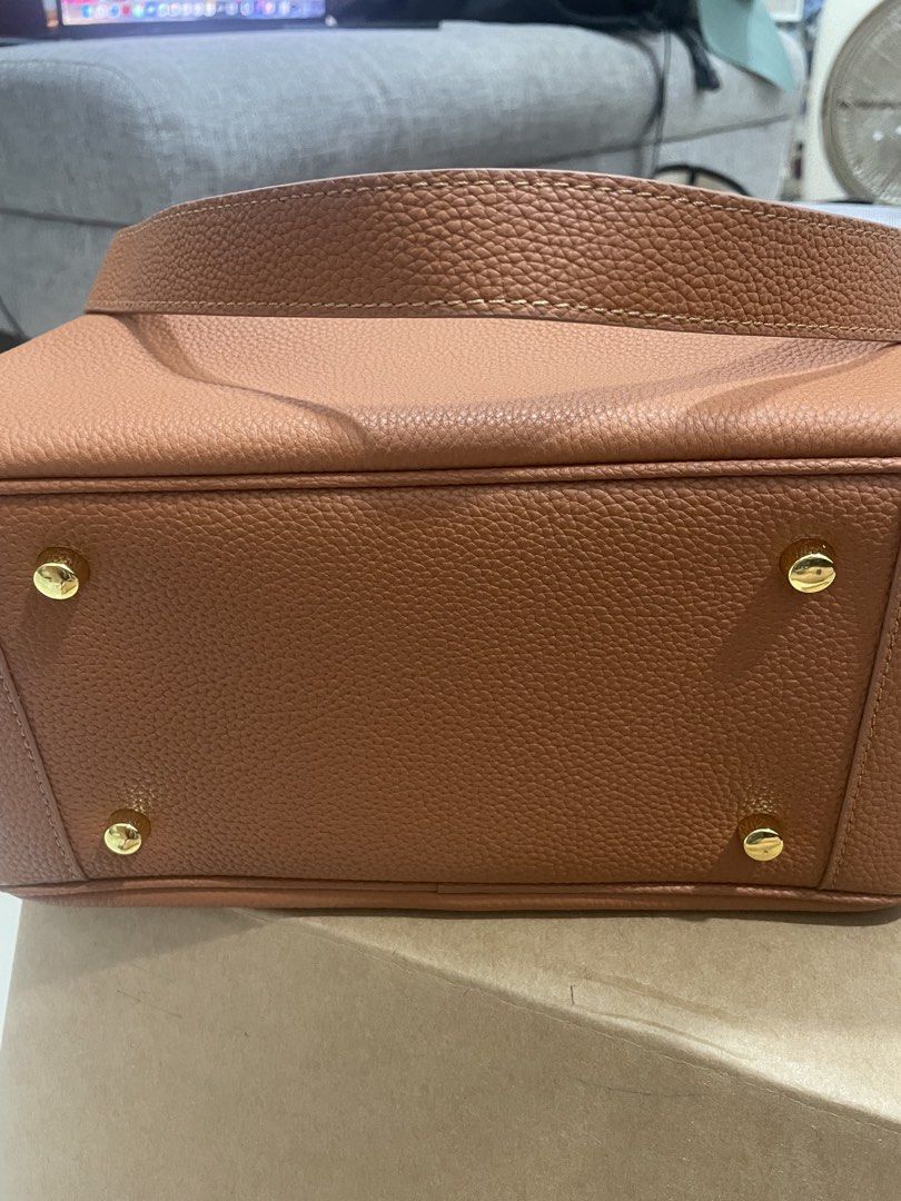 Brown Leather Top Handle Bag with Gold Hardware (Category: Shoulder Bags) located in Mandaluyong City. Submitted by annab11 (Listing ID 1465904170, Image 2). Description: - Style: Structured rectangular shoulder bag - Material: Premium tan pebbled leather with gold-tone hardware - Closure: Front flap with twist-lock and secure zippered top compartment - Versatility: Includes double top handles - Protection: Comes with metal feet underneath to pre