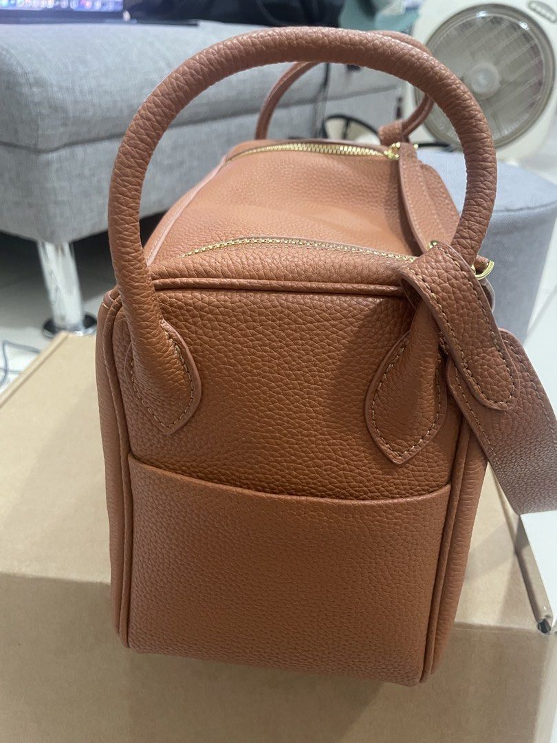 Brown Leather Top Handle Bag with Gold Hardware (Category: Shoulder Bags) located in Mandaluyong City. Submitted by annab11 (Listing ID 1465904170, Image 3). Description: - Style: Structured rectangular shoulder bag - Material: Premium tan pebbled leather with gold-tone hardware - Closure: Front flap with twist-lock and secure zippered top compartment - Versatility: Includes double top handles - Protection: Comes with metal feet underneath to pre