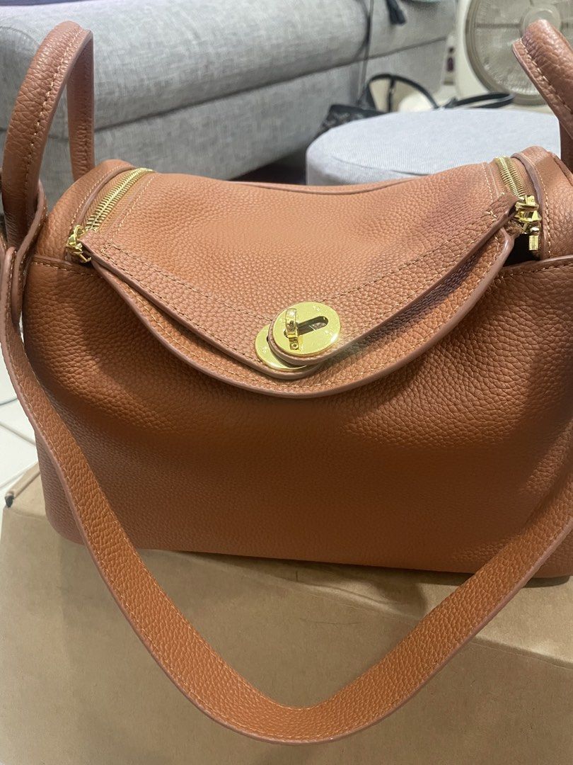 Brown Leather Top Handle Bag with Gold Hardware (Category: Shoulder Bags) located in Mandaluyong City. Submitted by annab11 (Listing ID 1465904170, Image 1). Description: - Style: Structured rectangular shoulder bag - Material: Premium tan pebbled leather with gold-tone hardware - Closure: Front flap with twist-lock and secure zippered top compartment - Versatility: Includes double top handles - Protection: Comes with metal feet underneath to pre