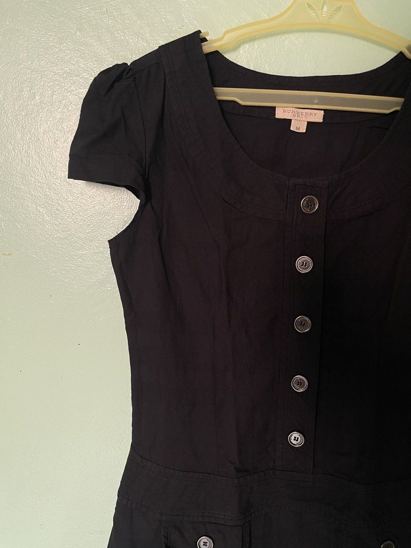 Burberry Brit Black Dress Size M (Category: Dresses) located in Baybay. Submitted by shikita27906 (Listing ID 1465845952, Image 2). Description: - Brand: Burberry Brit - Size: Medium - Color: Black with subtle tonal check pattern - Style: Classic fit and flare silhouette - Details: Short cap sleeves, round neckline, engraved button-down front, and two pleated waist pockets with button flaps.