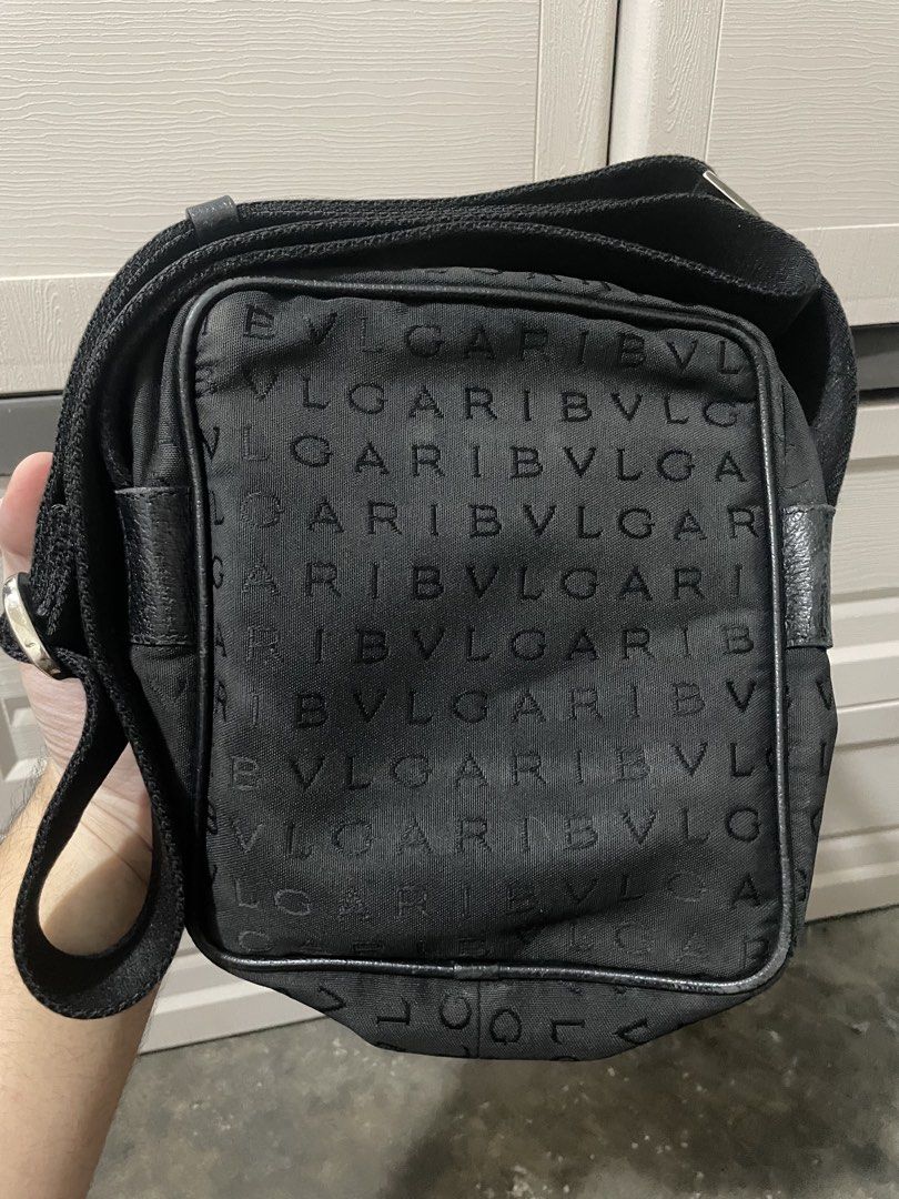 BVLGARI Crossbody Bag (Category: Luxury Bags & Wallets) located in Makati City. Submitted by danenavz (Listing ID 1465936384, Image 2). Description: - Brand: Bvlgari - Material: Black canvas with leather trim - Design: Logomania - Interior: Vibrant red lining with a secure zippered pocket - Closure: Top zipper closure - Strap: Adjustable for comfortable wear - Authenticity: Includes leather 'BVLGARI MADE IN ITALY' stamp and serial number tag at t