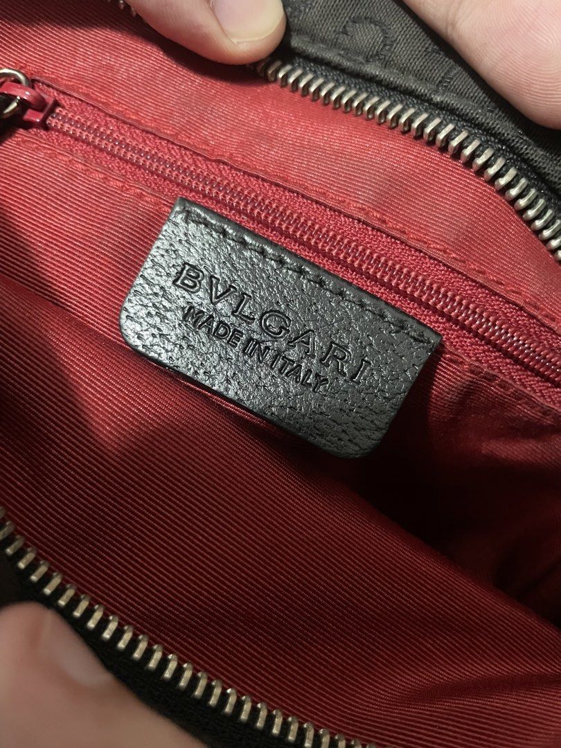 BVLGARI Crossbody Bag (Category: Luxury Bags & Wallets) located in Makati City. Submitted by danenavz (Listing ID 1465936384, Image 3). Description: - Brand: Bvlgari - Material: Black canvas with leather trim - Design: Logomania - Interior: Vibrant red lining with a secure zippered pocket - Closure: Top zipper closure - Strap: Adjustable for comfortable wear - Authenticity: Includes leather 'BVLGARI MADE IN ITALY' stamp and serial number tag at t