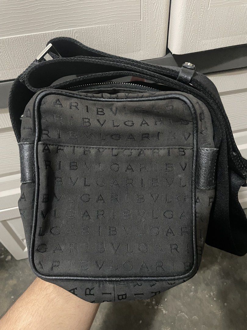 BVLGARI Crossbody Bag (Category: Luxury Bags & Wallets) located in Makati City. Submitted by danenavz (Listing ID 1465936384, Image 1). Description: - Brand: Bvlgari - Material: Black canvas with leather trim - Design: Logomania - Interior: Vibrant red lining with a secure zippered pocket - Closure: Top zipper closure - Strap: Adjustable for comfortable wear - Authenticity: Includes leather 'BVLGARI MADE IN ITALY' stamp and serial number tag at t