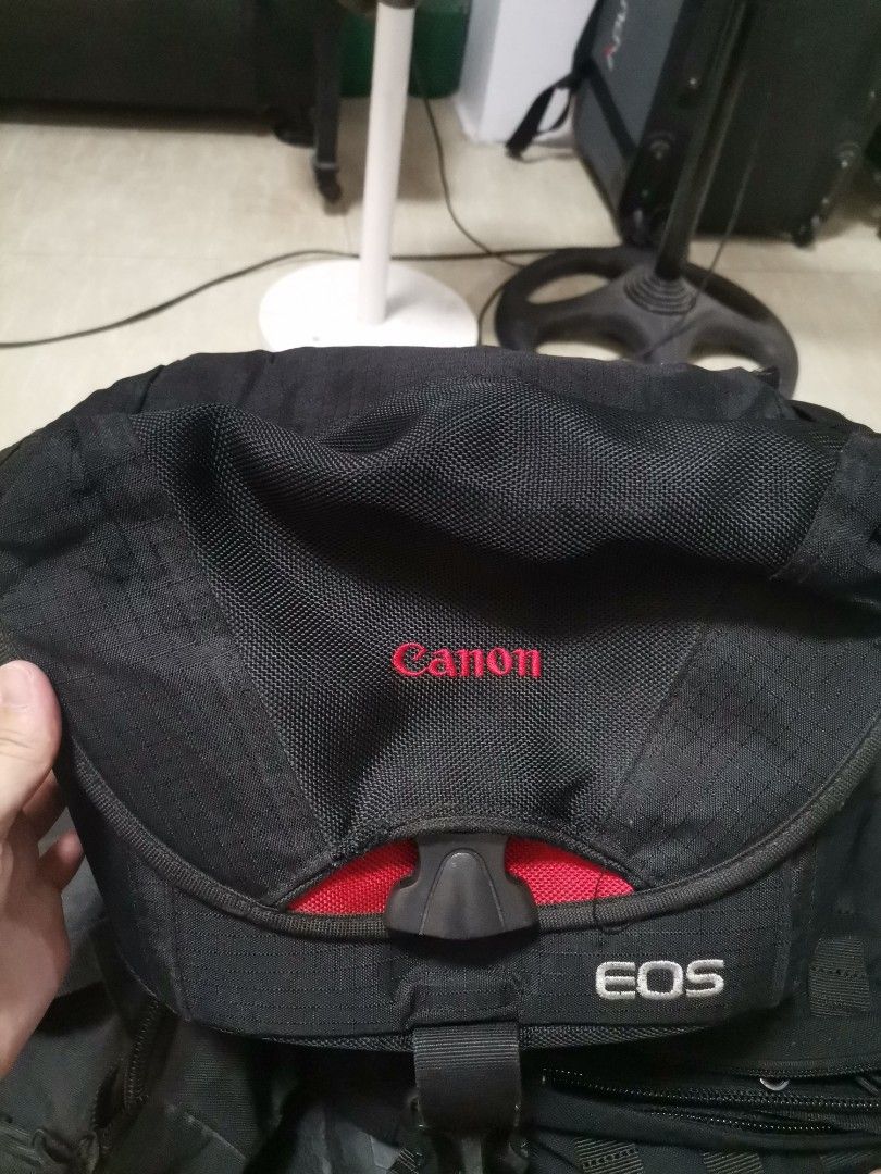 Canon EOS Camera Shoulder Bag Black Red (Category: Camera Bags & Carriers) located in Makati City. Submitted by kookybearsstuff (Listing ID 1465817288, Image 2). Description: - Authentic Canon & EOS embroidered branding - Durable black nylon material with vibrant red interior lining - Secure plastic buckle closure and top grab handle - Adjustable padded divider inside for organized gear storage - Breathable mesh back padding for comfortable carry