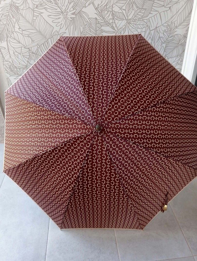 Celine Brown Monogram Umbrella (Category: Luxury Accessories) located in Siniloan. Submitted by treyyasonlineshop (Listing ID 1465767431, Image 2). Description: - Authentic Celine umbrella in classic brown monogram print - Features a metallic bronze curved handle with stamped Celine logo hardware - Canopy fabric and frame structure are clean and fully functional - Note: Handle shows light scratches and scuffs from previous use.
