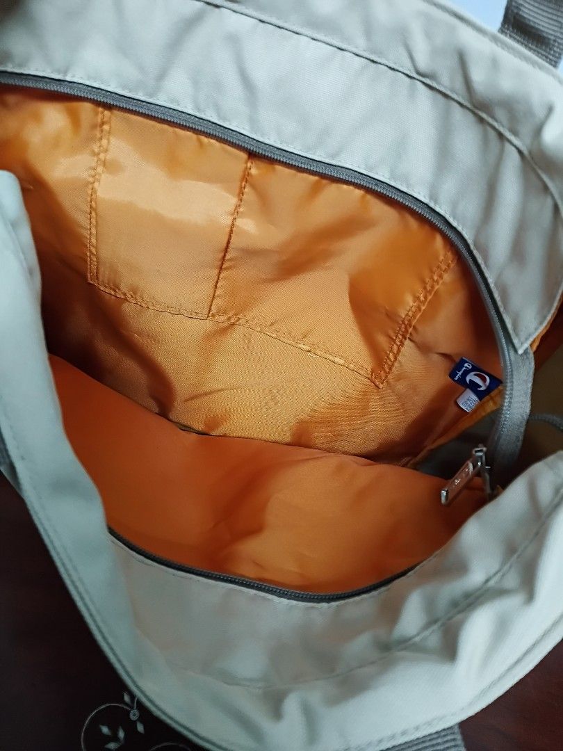 Champion Canvas Tote Bag Beige (Category: Tote Bags) located in Quezon City. Submitted by fateonlineshop (Listing ID 1465797267, Image 2). Description: - Brand: Champion - Color: Beige canvas with a vibrant orange nylon interior - Straps: Sturdy dual shoulder straps for comfortable carrying - Pockets: Large exterior front zip pocket and interior slip pockets for organization - Condition: Clean inside and out, very durable construction - Ideal Use