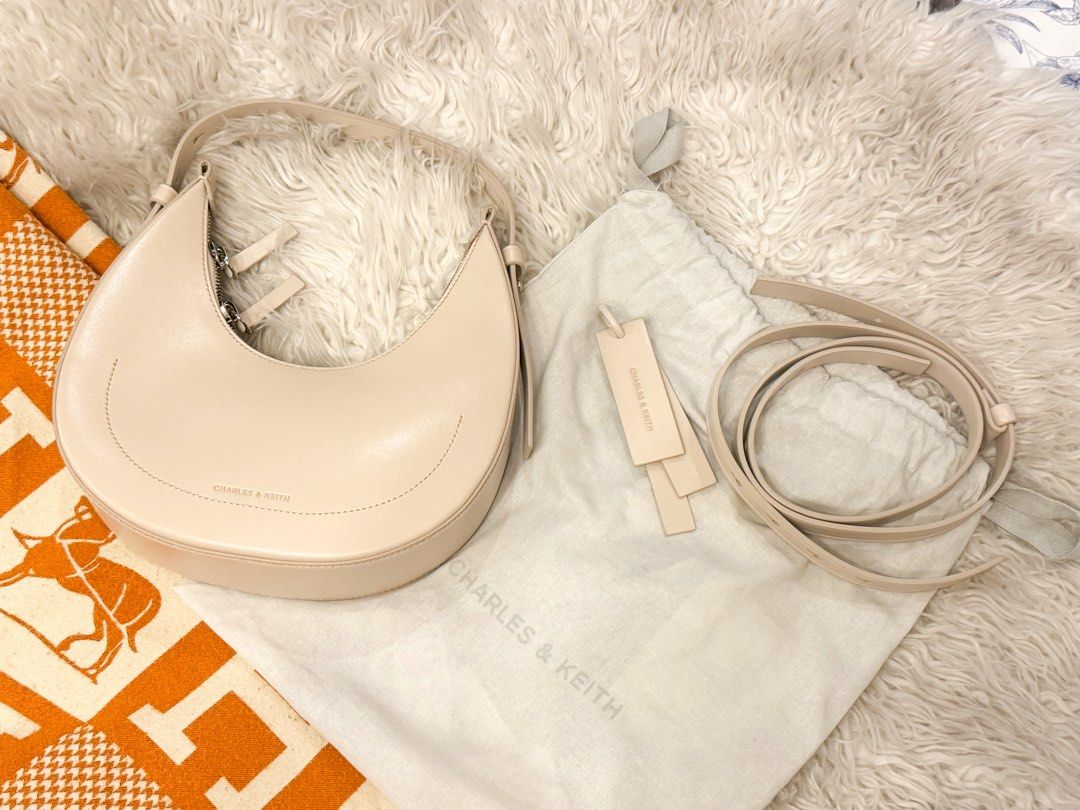 Charles & Keith Cream Crescent Shoulder Bag (Category: Shoulder Bags) located in Manila. Submitted by jairahncle (Listing ID 1465913327, Image 3). Description: - Brand: Charles & Keith - Style: Curved crescent shape bag - Color: Cream with chic silver hardware - Condition: Brand new with tags, includes original dust bag - Features: Clean smooth finish, structured base to hold its shape, and an adjustable extra-long strap inside - RFS: Declutterin