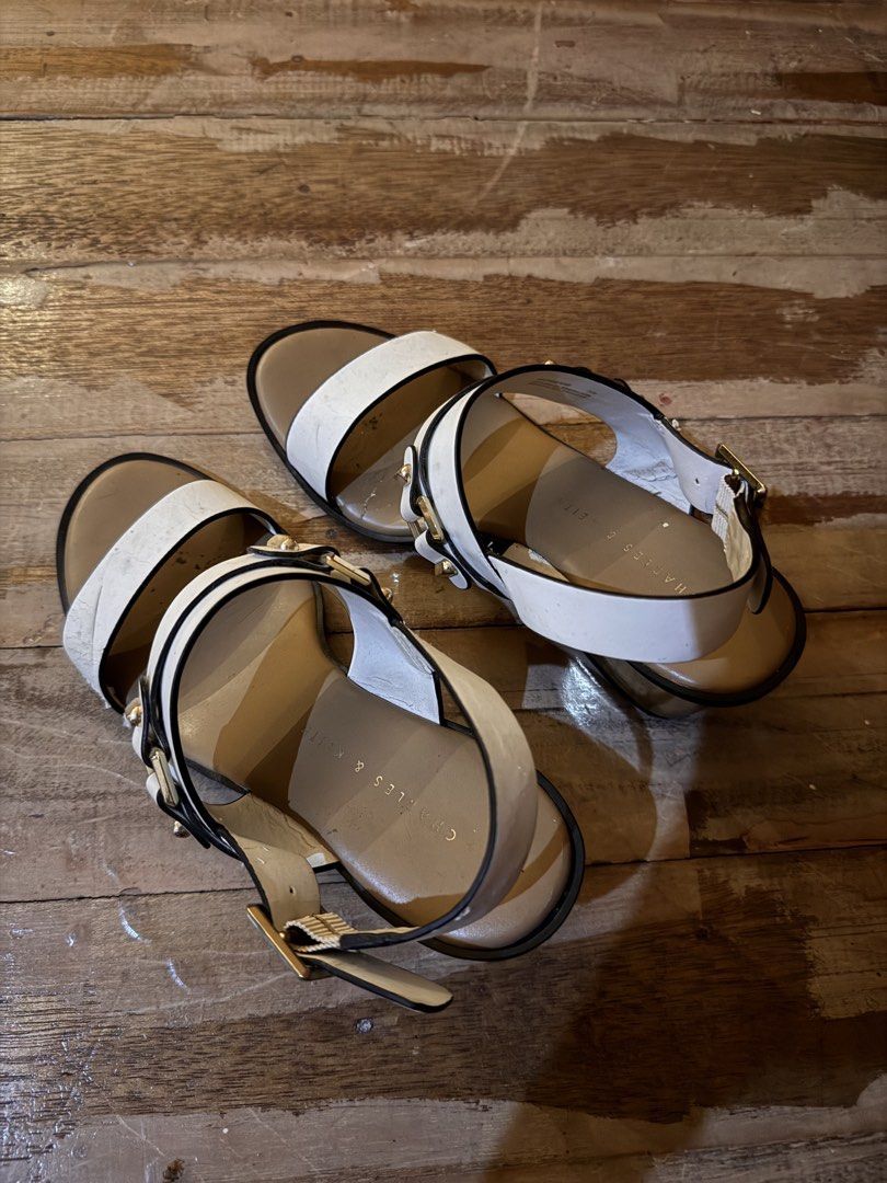 Charles & Keith White Block Heel Sandals Size 35 (Category: Heels) located in Pasig City. Submitted by klaaaaa (Listing ID 1465878155, Image 3). Description: - Brand: Charles & Keith - Style: White sandals with gold block heels, double front straps, and gold buckle hardware - Fit: Slingback strap with adjustable closure, Size 35 - Details: Tan inner sole with clear branding - Condition: Visible wear, creasing on the white material, and some scuff