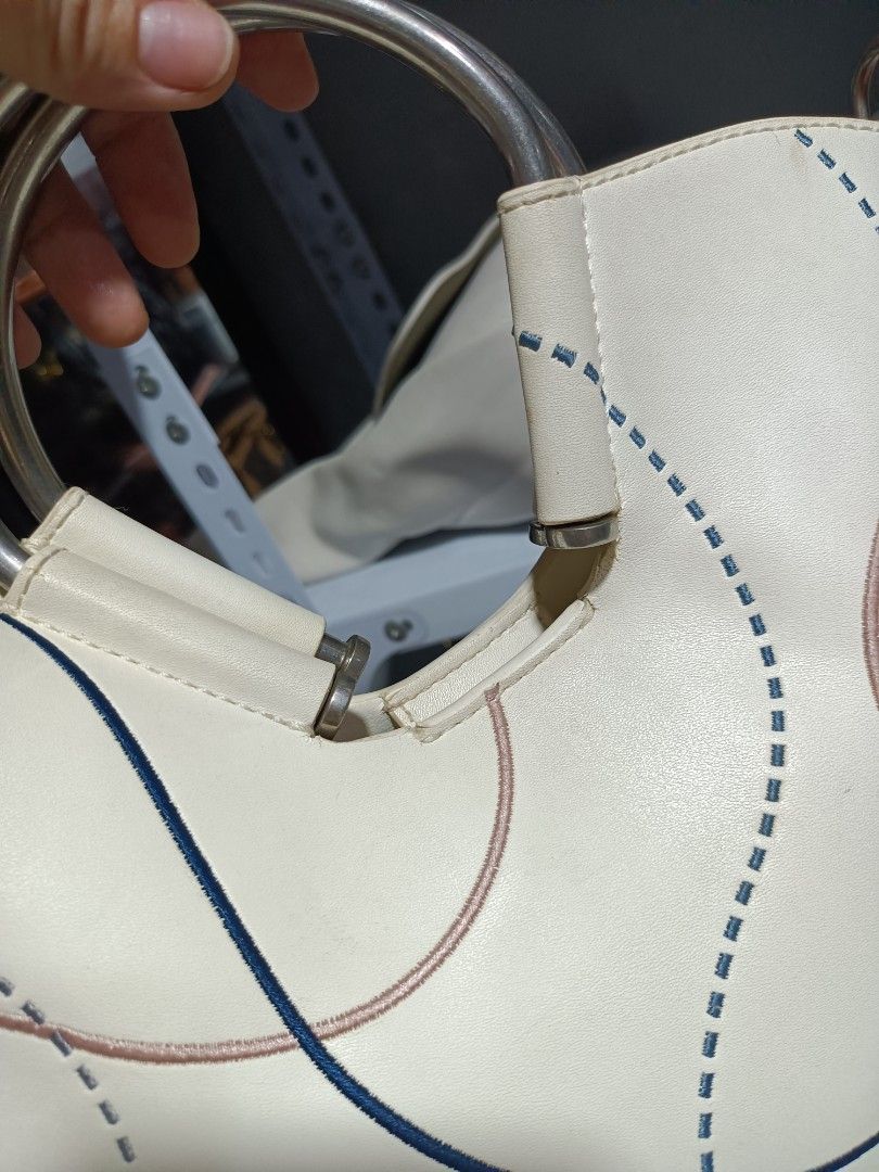 Charles & Keith White Half Moon Bag (Category: Shoulder Bags) located in Naga. Submitted by zksboutique (Listing ID 1465936791, Image 3). Description: - Trendy half moon shape in off-white - Unique blue and pink stitched curved line details on the front - Elegant silver top handles and matching adjustable shoulder strap - Chic gold brand lettering near the bottom edge - Compact and convenient size for daily essentials - Secure zip closure to keep