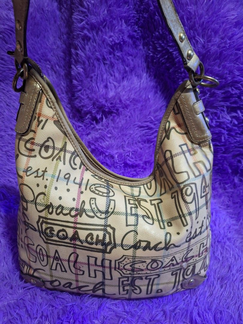 Coach Graffiti Print Hobo Bag (Category: Luxury Bags & Wallets) located in Quezon City. Submitted by cloudymay (Listing ID 1465885864, Image 2). Description: - Brand: Coach - Style: Hobo bag with single shoulder strap - Design: Signature graffiti typography and plaid print on cream background - Hardware: Metallic gold with leather trim - Interior: Includes a zipped compartment - Condition: Good structured shape with minor wear on leather strap ed