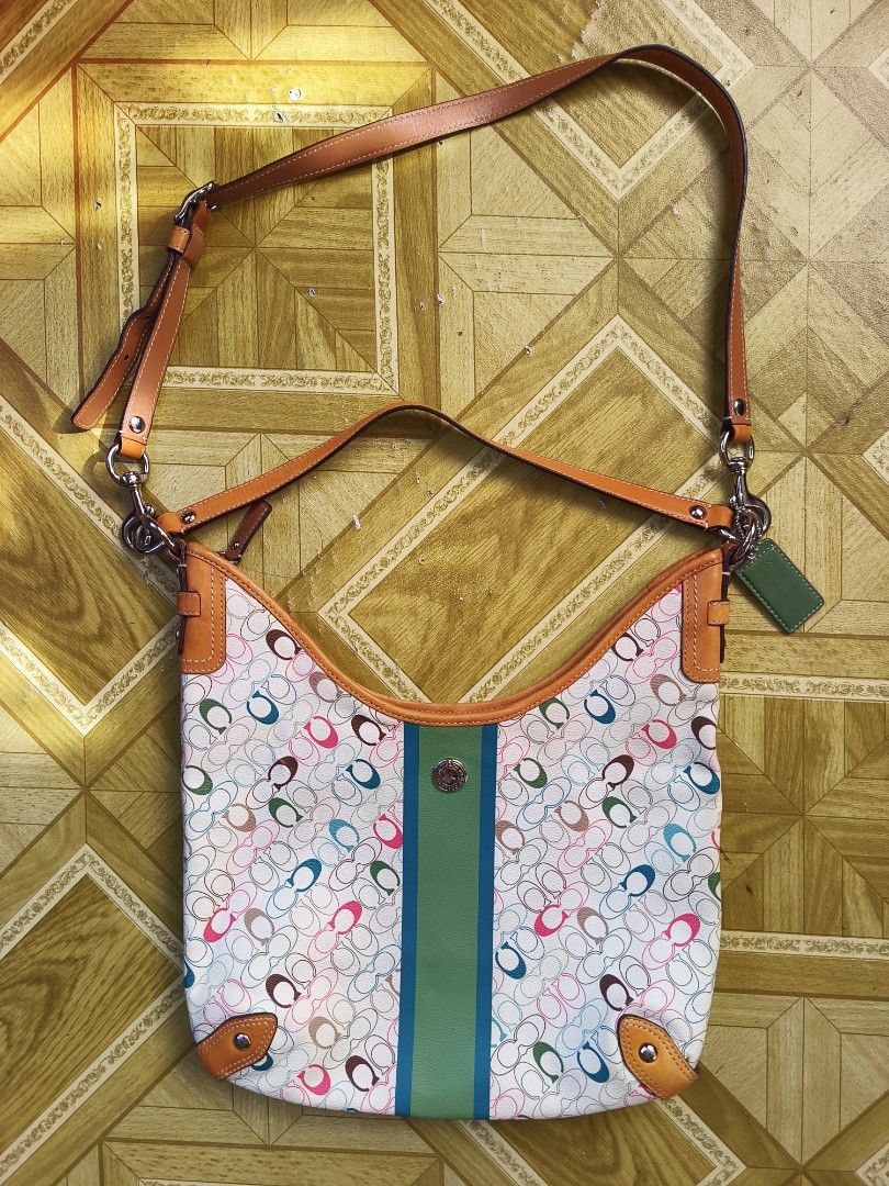 Coach Multi-Color Signature C Hobo Bag (Category: Luxury Bags & Wallets) located in Ilagan. Submitted by alamistad493 (Listing ID 1465762965, Image 3). Description: - Authentic Coach hobo bag - Multi-color signature C print on white canvas - Tan leather strap, corner trim, and green leather hangtag - Eye-catching green and blue center stripe - Secure top zipper closure - Brown fabric lining with interior creed patch (Serial No: C1069-F15138) - Po
