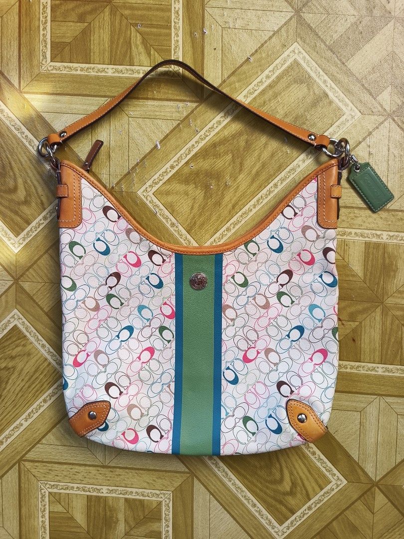 Coach Multi-Color Signature C Hobo Bag (Category: Luxury Bags & Wallets) located in Ilagan. Submitted by alamistad493 (Listing ID 1465762965, Image 2). Description: - Authentic Coach hobo bag - Multi-color signature C print on white canvas - Tan leather strap, corner trim, and green leather hangtag - Eye-catching green and blue center stripe - Secure top zipper closure - Brown fabric lining with interior creed patch (Serial No: C1069-F15138) - Po