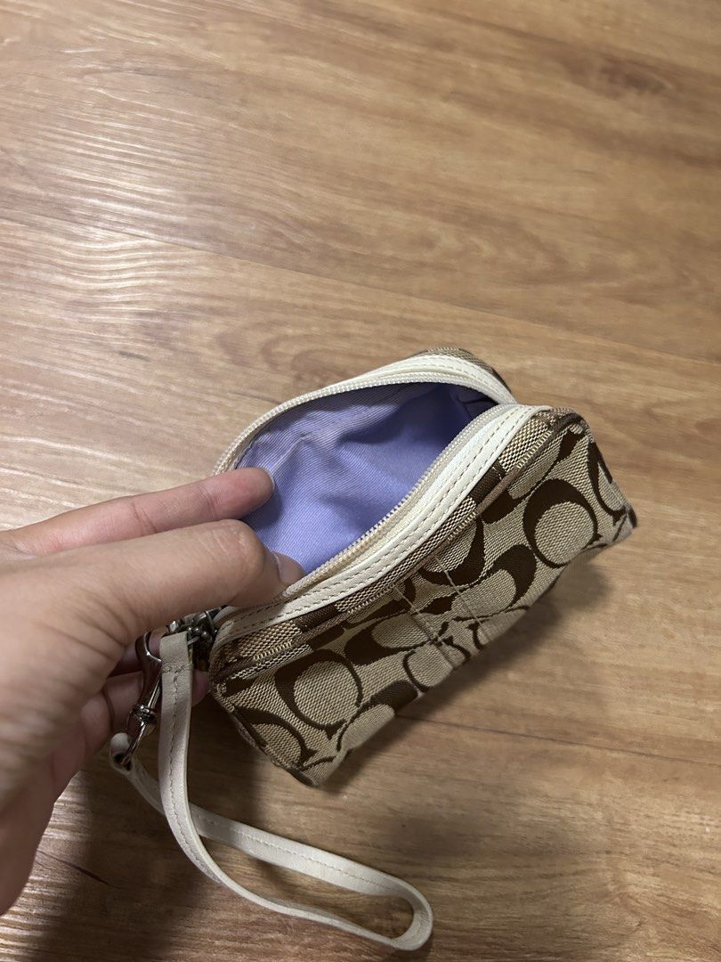 Coach Signature C Wristlet (Category: Luxury Bags & Wallets) located in Del Monte. Submitted by antonja (Listing ID 1465863455, Image 2). Description: - Brand: Coach - Design: Classic brown signature C monogram with chic white leather trim - Hardware: Polished silver-tone hardware with iconic Coach hangtag - Closure: Secure zip-top closure - Interior: Clean solid light purple fabric lining - Convenience: Includes matching white leather wrist stra