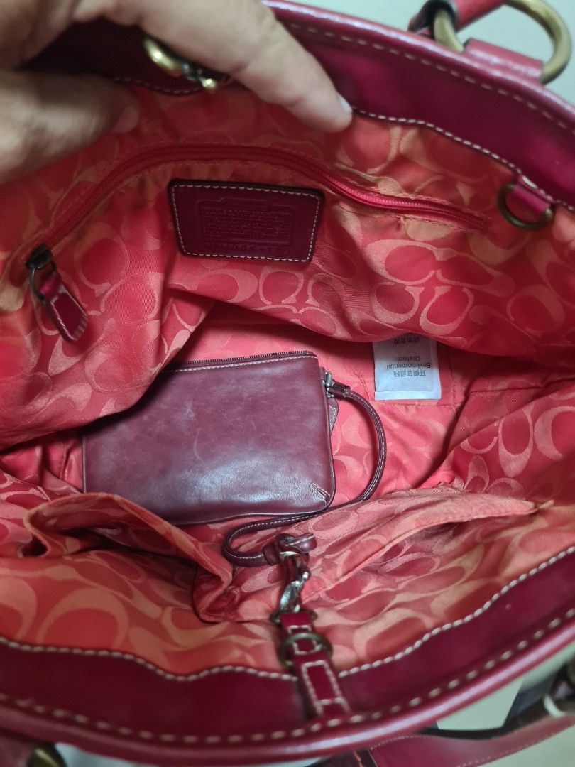Coach Straw and Red Leather Handbag (Category: Luxury Bags & Wallets) located in Manila. Submitted by sevyaleinad (Listing ID 1465777382, Image 3). Description: - Brand: Coach - Material: Straw weave with dark red leather trim - Interior: Vibrant pink fabric lining with signature C pattern - Compartments: Front pocket with buckle detail, interior zipper, and slip pockets - Closure: Top zipper with dual handles - Authenticity: Serial number stamp 