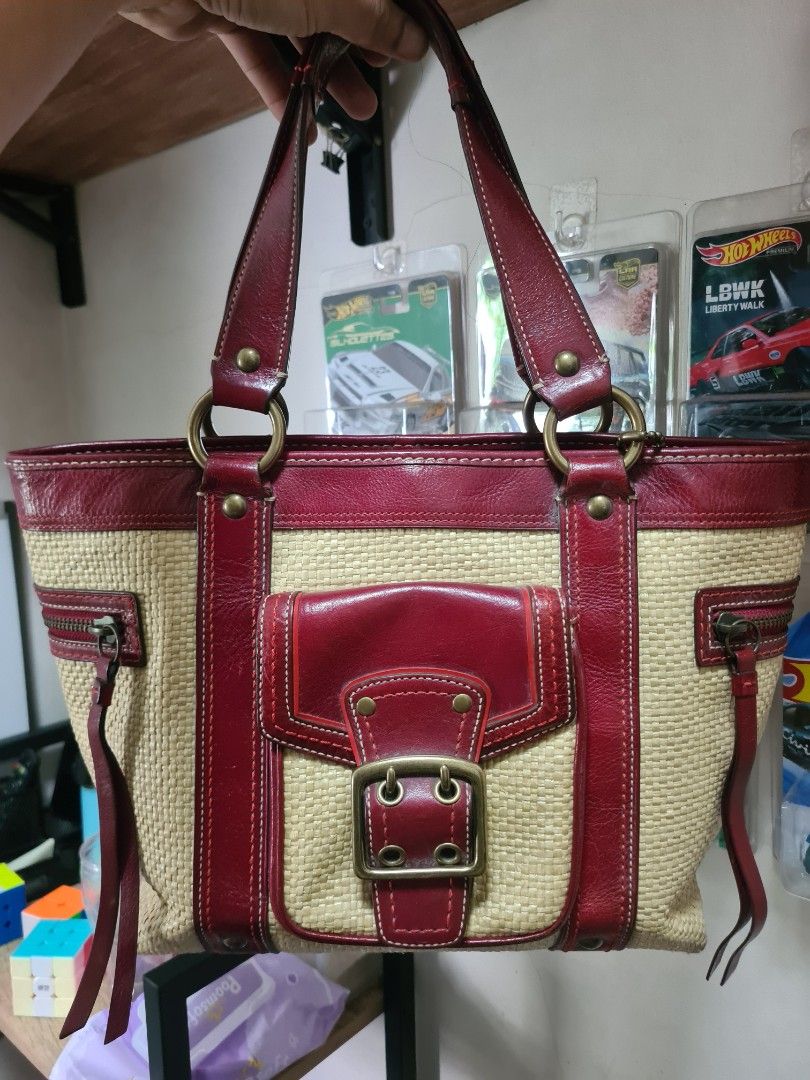 Coach Straw and Red Leather Handbag (Category: Luxury Bags & Wallets) located in Manila. Submitted by sevyaleinad (Listing ID 1465777382, Image 1). Description: - Brand: Coach - Material: Straw weave with dark red leather trim - Interior: Vibrant pink fabric lining with signature C pattern - Compartments: Front pocket with buckle detail, interior zipper, and slip pockets - Closure: Top zipper with dual handles - Authenticity: Serial number stamp 
