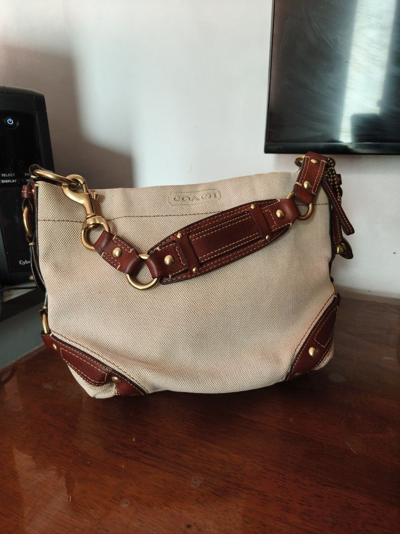 Coach Tan Canvas and Brown Leather Shoulder Bag (Category: Shoulder Bags) located in Caloocan City. Submitted by ehmrys_024 (Listing ID 1465763499, Image 1). Description: - Authentic Coach shoulder bag in tan canvas - Rich brown leather trim and brass-tone hardware - Structured, slouchy shape with contrast stitching - Detailed strap links featuring gold stud accents - Debossed Coach logo on the front fabric panel - Zipper closure with attached pu