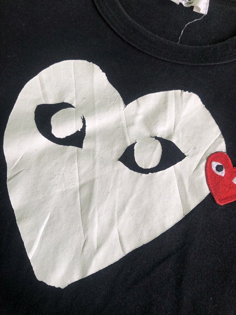 COMME des GARÇONS PLAY Black Heart Tee Size M (Category: Activewear) located in Cagayan de Oro. Submitted by leklekthrift (Listing ID 1465891611, Image 2). Description: - Brand: COMME des GARÇONS PLAY - Item: Black T-Shirt - Size: Medium - Material: 100% Cotton (Made in Japan) - Design: Large white heart chest print with black eyes and signature red embroidered heart badge - Condition: Interior neck and care labels intact; minor wrinkles on the l