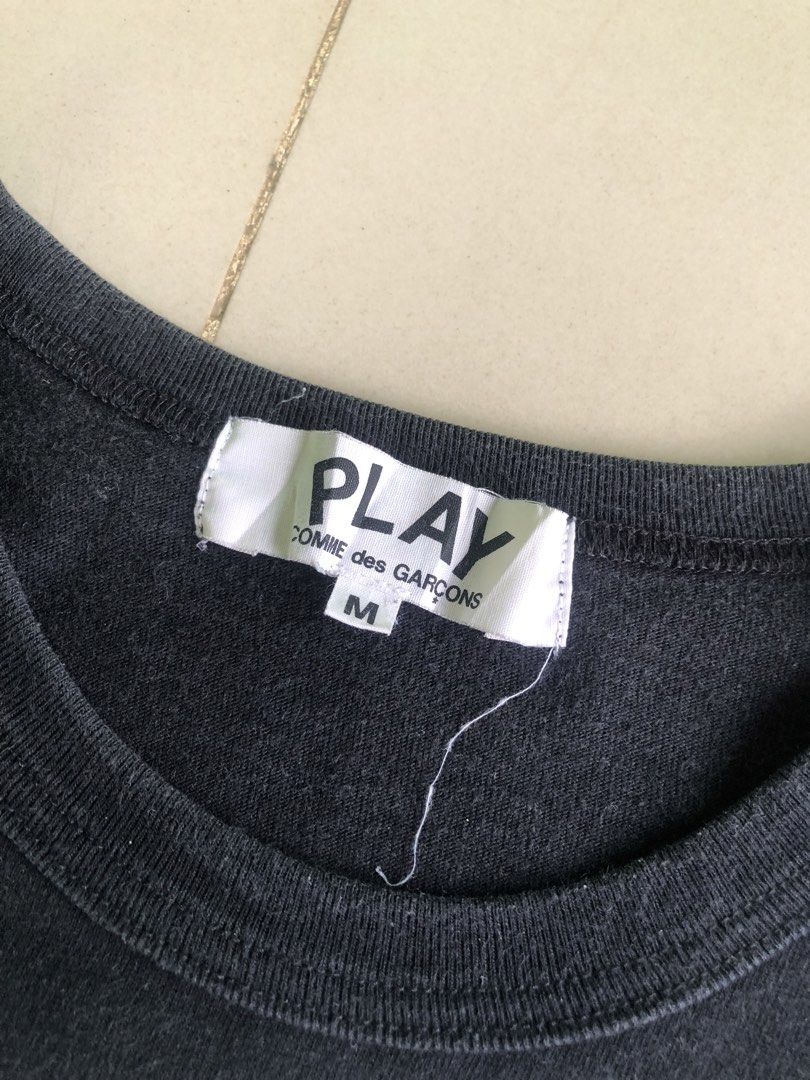COMME des GARÇONS PLAY Black Heart Tee Size M (Category: Activewear) located in Cagayan de Oro. Submitted by leklekthrift (Listing ID 1465891611, Image 3). Description: - Brand: COMME des GARÇONS PLAY - Item: Black T-Shirt - Size: Medium - Material: 100% Cotton (Made in Japan) - Design: Large white heart chest print with black eyes and signature red embroidered heart badge - Condition: Interior neck and care labels intact; minor wrinkles on the l