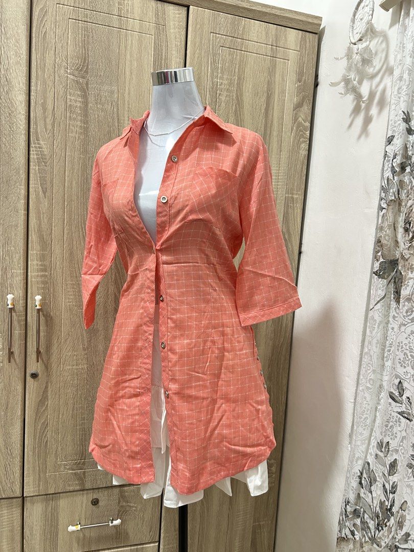 Coral Checkered Button-Up Tunic Shirt (Category: Blouses) located in Cavite. Submitted by cl09-39734 (Listing ID 1465820957, Image 1). Description: - Color: Coral orange with white checkered grid pattern - Sleeves: Three-quarter sleeves - Closure: Button-down front - Details: Functional chest pockets - Fit: Mid-length tunic style - Versatility: Great for casual wear or layering.
