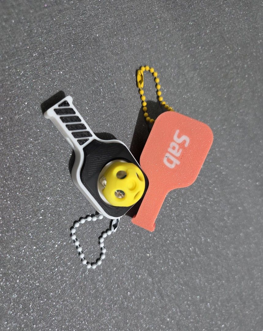 Custom 3D Pickleball Paddle Clicker and Whistle charm (Category: Racket and Ball Sports) located in Quezon City. Submitted by cottoncandyqc (Listing ID 1465919514, Image 1). Description: - Fun 3D-printed miniature pickleball paddle keychain featuring a clicker mini ball - also functions as a whistle - Customizable with names/text (add 20p) (3-7 days for bulk orders) - Multi-color sturdy but lightweight PLA with optional silver keychain - Durable 