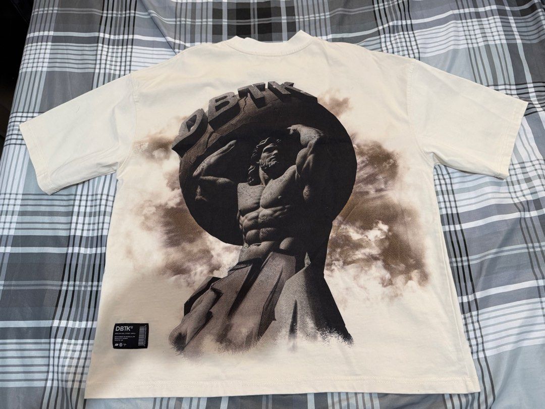 DBTK Evermore Atlas Graphic Tee Cream (Category: Tshirts & Polo Shirts ) located in Pasig City. Submitted by rchsh (Listing ID 1465847673, Image 2). Description: - Brand: DBTK (Evermore Collection) - Color: Cream - Design: Small embroidered chest logo, large Atlas graphic on the back - Fit: Short sleeves, relaxed boxy fit - Details: Woven label on the bottom hem - Condition: 10/10, clean fabric with no flaws and intact graphics.