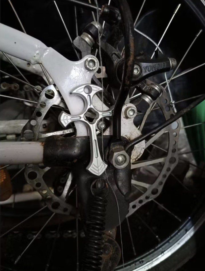 Decorative Cross Shape Mount For Bicycle Frame (Category: Bicycles) located in Quezon City. Submitted by liana.finds (Listing ID 1465797228, Image 1). Description: - Material: Solid metal with machined detailing - Placement: Mounts near rear disc brake and kickstand - Style: Adds a custom, edgy look to your bike - Installation: Uses existing bike frame bolts for easy setup - Compatibility: Fits standard bicycle frames with rear mount areas.