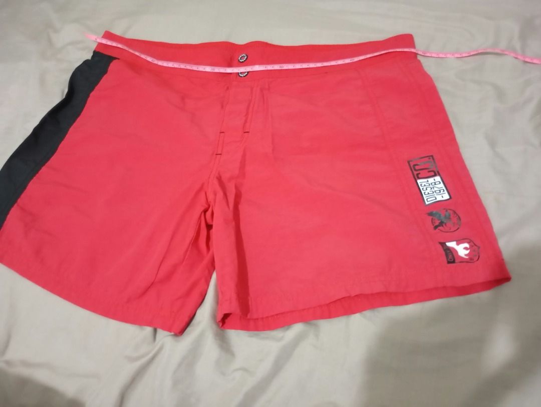 Diesel Red Swim Shorts (Men) (Category: Shorts) located in Pasig City. Submitted by ajms63804 (Listing ID 1465783180, Image 1). Description: - Brand: Diesel - Size: Fits 36" to 38'" - Color: Red with black side panels - Details: Graphic logo print on lower left leg - Pocket: Single back pocket with button closure - Fit: Comfortable for beach days or casual wear - Sizing: Waistband measurement shown in photos.