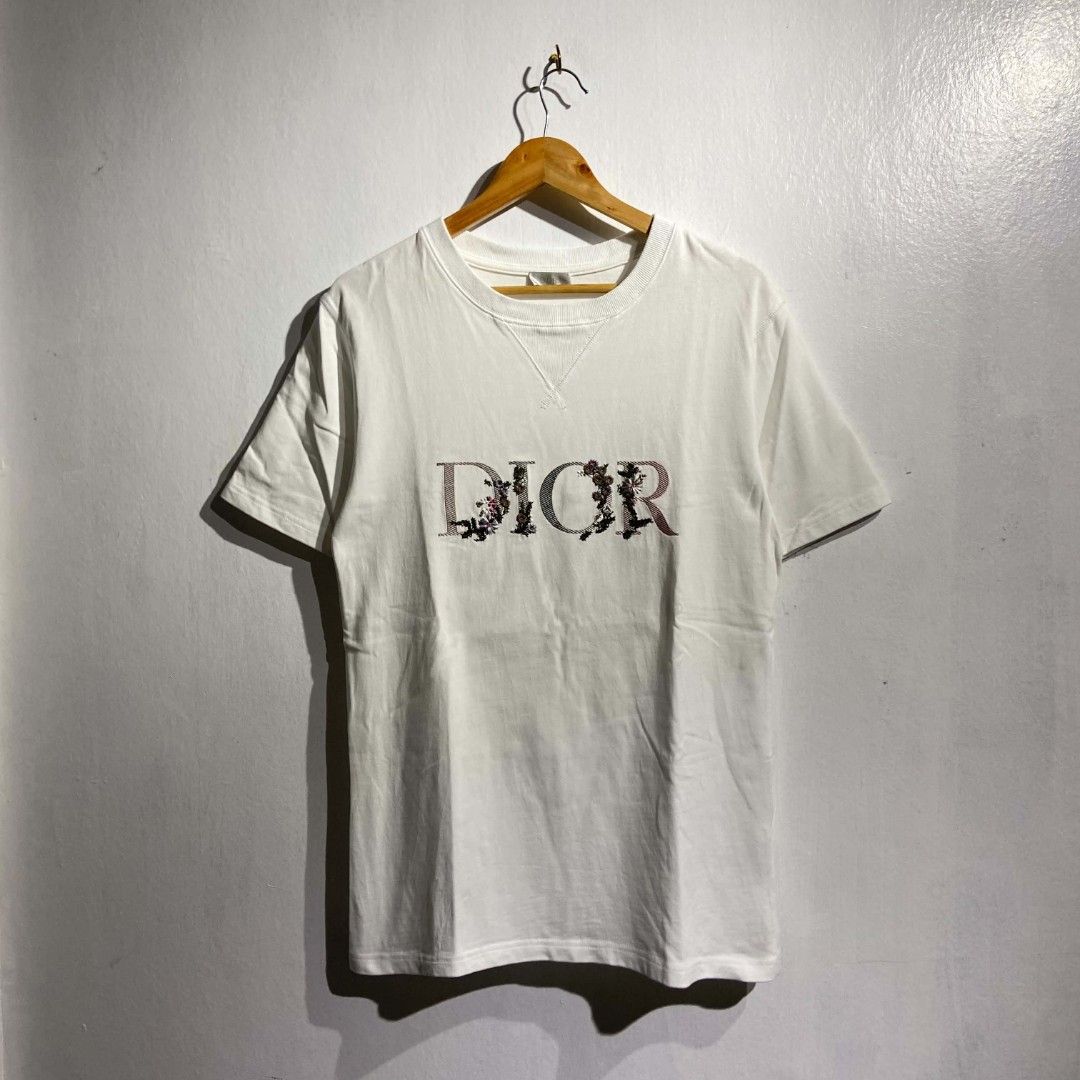 Dior Flower (Category: Luxury Apparel) located in Manila. Submitted by lumang__gamit00 (Listing ID 1465802629, Image 1). Description: The white cotton tee features a distinctive "DIOR" chest logo filled with colorful floral embroidery 20-29 no issue.