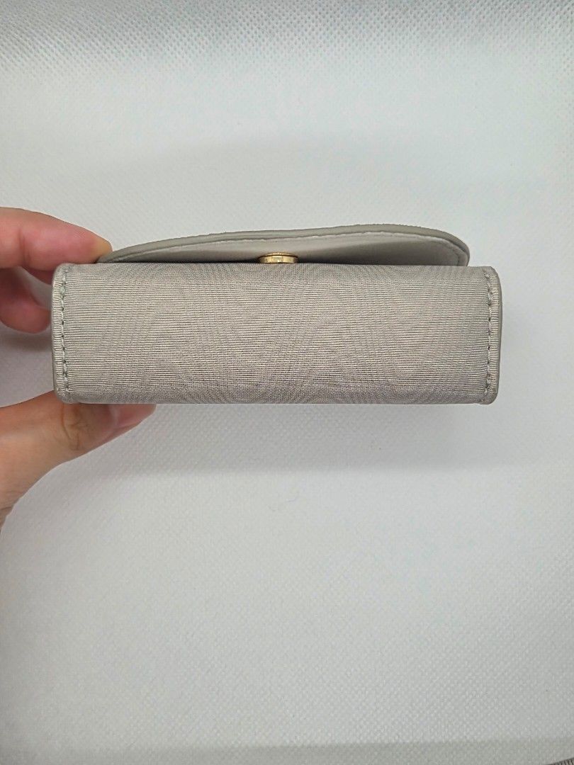 Dior Grey Fabric Jewelry Case (Category: Accessory Holder, Box & Organizers) located in Manila. Submitted by prelovedbyc.hannah (Listing ID 1465849509, Image 3). Description: - Brand: Dior - Material: Grey textured fabric with clean white interior lining - Accents: Signature gold Dior logo on front flap - Closure: Secure magnetic snap - Storage: Padded rolls designed to hold multiple rings securely - Size: Approximately 12 cm long - Condition: Ex