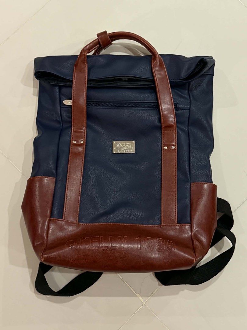 d.kelly 1985 Navy and Brown Backpack (Category: Backpacks) located in Cabuyao City. Submitted by seokjinspree (Listing ID 1465761895, Image 1). Description: Brand: D.Kelly 1985 Color: Navy blue with stylish brown faux leather trim Carry Options: Dual top carry handles and adjustable black shoulder straps Storage: Front zipper pocket and a spacious main compartment Details: Metallic brand plaque and embossed lettering on the lower front.