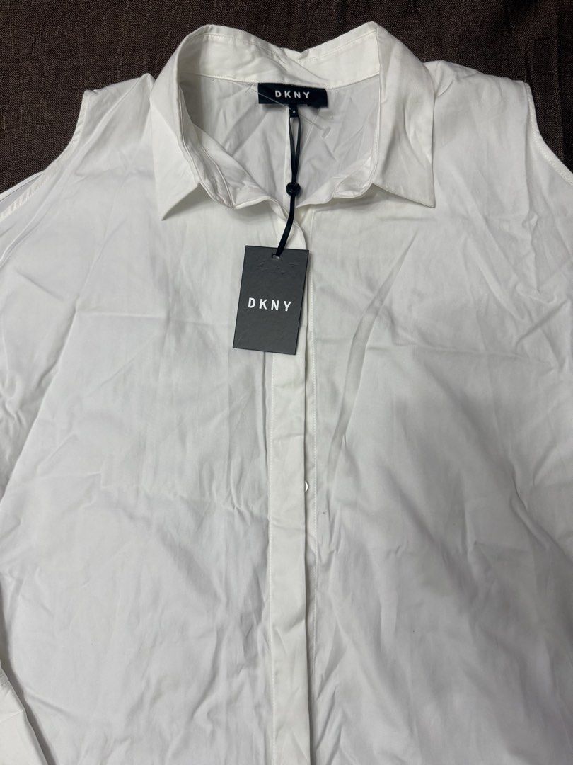 DKNY White Cold Shoulder Button-Up Shirt (Category: Shirts) located in Quezon City. Submitted by mt031199 (Listing ID 1465947437, Image 3). Description: - Brand: DKNY (Original tag still attached) - Color: Classic White - Style: Button-up shirt with trendy cold shoulder cutouts on both sleeves - Features: Long sleeves with button cuffs, classic collar, and front button placket - Condition: Brand new with tags (BNWT).