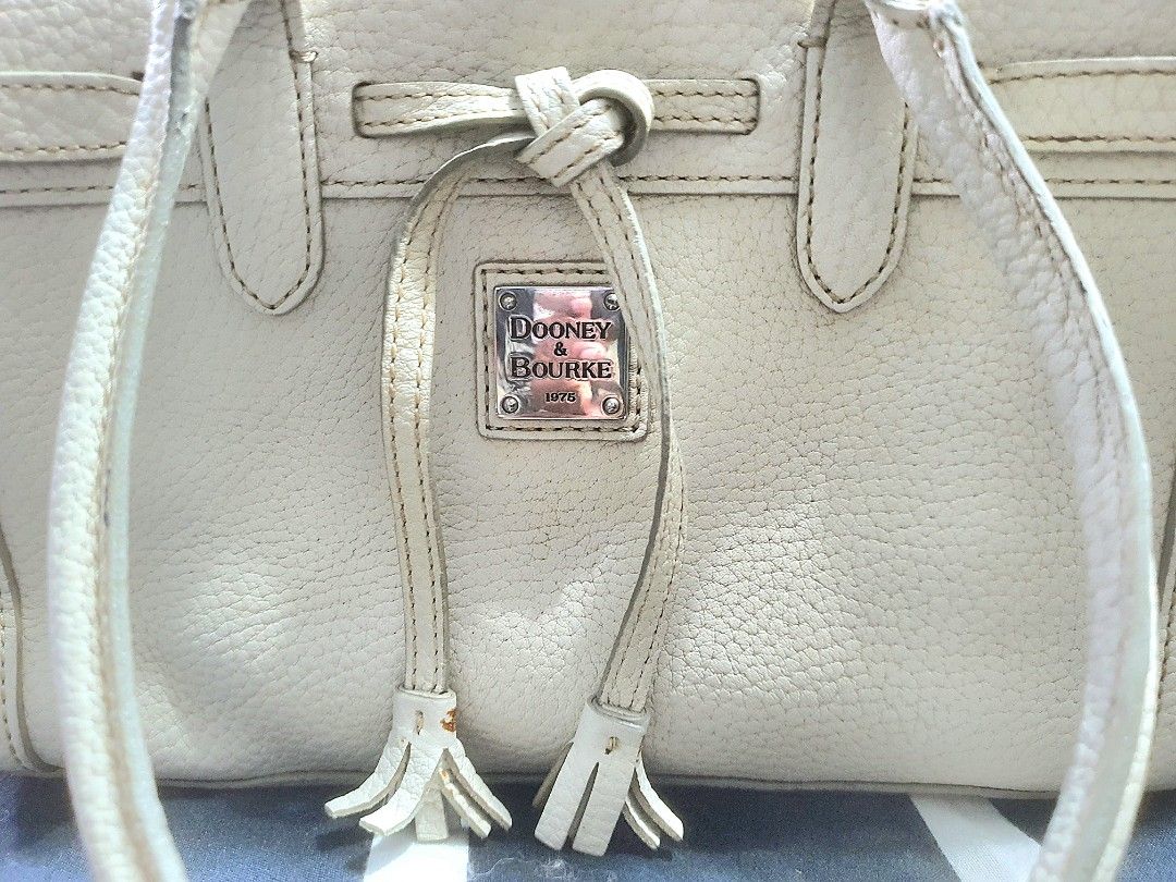 Dooney & Bourke Beige Leather Tote Bag (Category: Luxury Bags & Wallets) located in Manila. Submitted by mozaitv1236506 (Listing ID 1465928071, Image 2). Description: - Brand: Dooney & Bourke - Material: Premium beige pebble leather - Hardware: Silver-tone front plaque with stylish tassel pull strings - Straps: Comfortable double shoulder straps - Interior: Vibrant patterned fabric lining with a zipper pocket, slip pocket, and attached key leash 