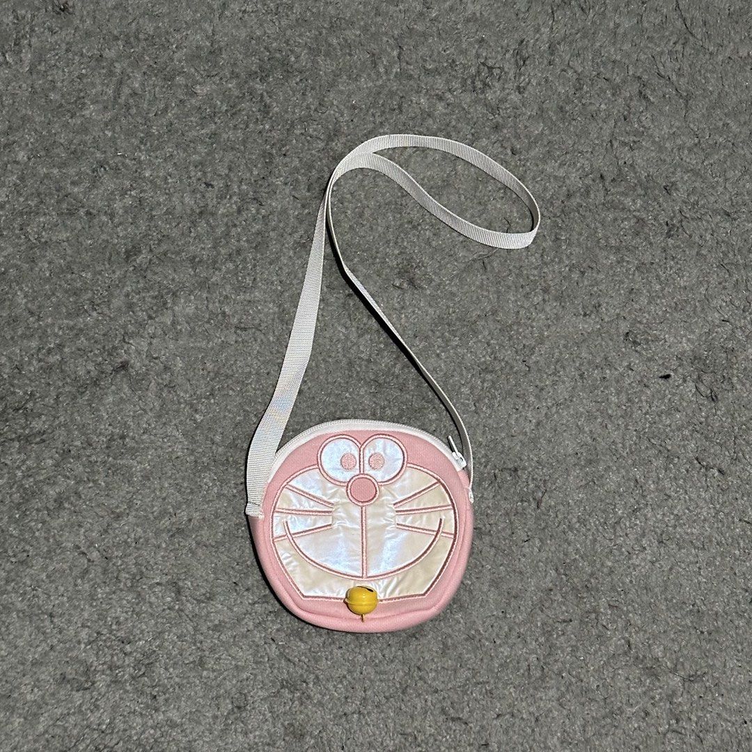 Doraemon Pink Round Crossbody Bag with Strap (Category: Cross-body Bags) located in Lipa City. Submitted by jecoparra (Listing ID 1465918897, Image 1). Description: - Adorable pink round crossbody bag featuring a cute Doraemon face design - Includes a signature small yellow bell dangling near the bottom zipper - Features a clean solid pink fabric on the back - Convenient top zipper closure to keep your essentials secure - Equipped with an attache