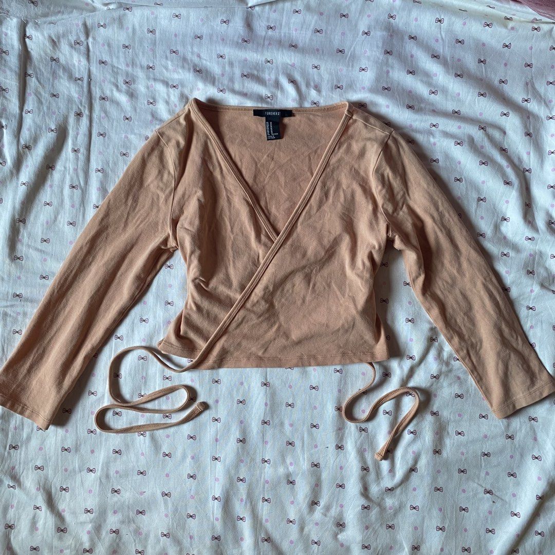 Forever 21 Peach Wrap Crop Top Size M (Category: Sleeveless) located in Abulug. Submitted by dear_darlingdoll (Listing ID 1465846963, Image 1). Description: - Brand: Forever 21 - Size: M - Color: Peach - Material: 95% cotton, 5% spandex (soft and stretchy) - Design: Wrap style, V-neckline, long sleeves, side tie closure - Styling: Perfect to pair with high-waisted jeans or skirts.