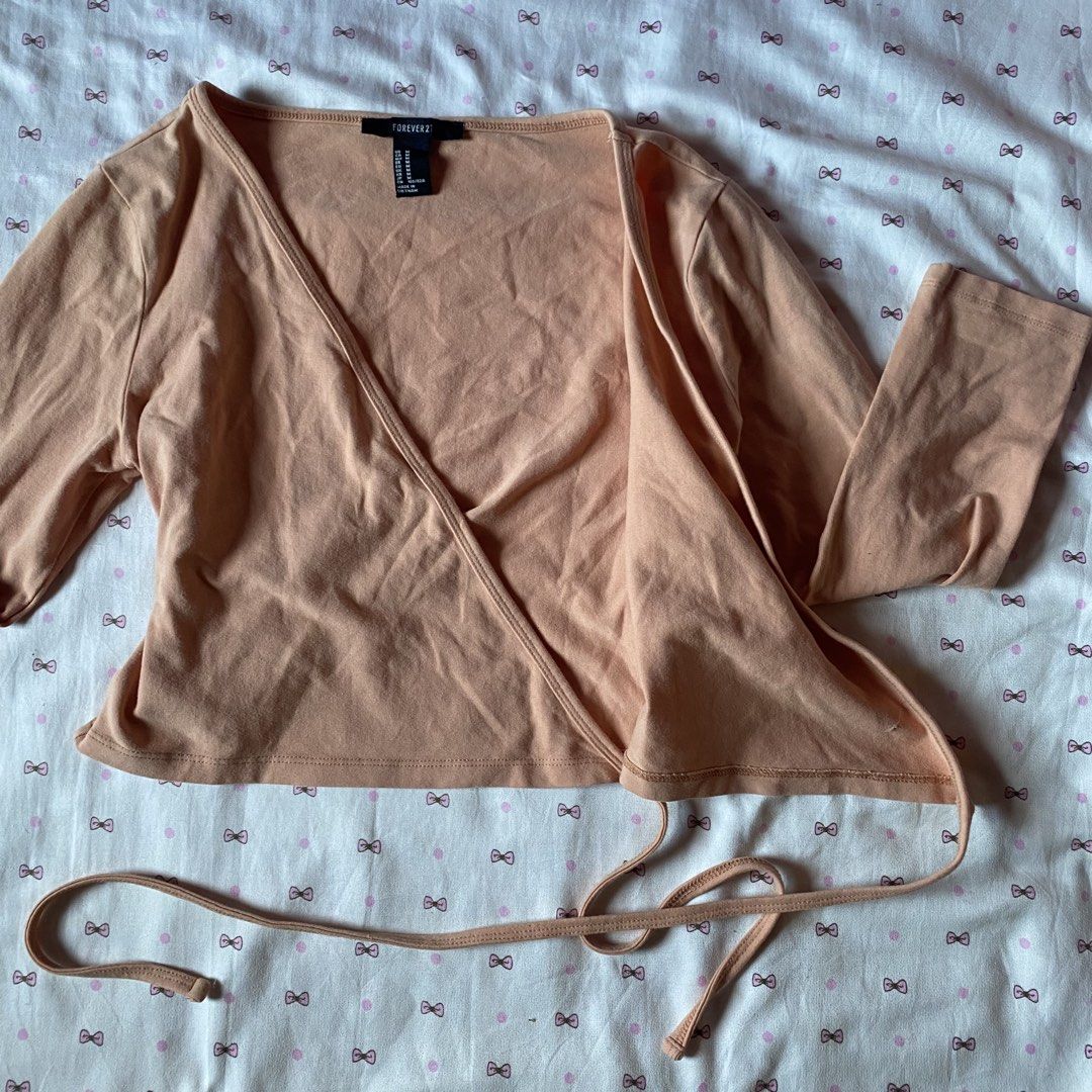 Forever 21 Peach Wrap Crop Top Size M (Category: Sleeveless) located in Abulug. Submitted by dear_darlingdoll (Listing ID 1465846963, Image 2). Description: - Brand: Forever 21 - Size: M - Color: Peach - Material: 95% cotton, 5% spandex (soft and stretchy) - Design: Wrap style, V-neckline, long sleeves, side tie closure - Styling: Perfect to pair with high-waisted jeans or skirts.