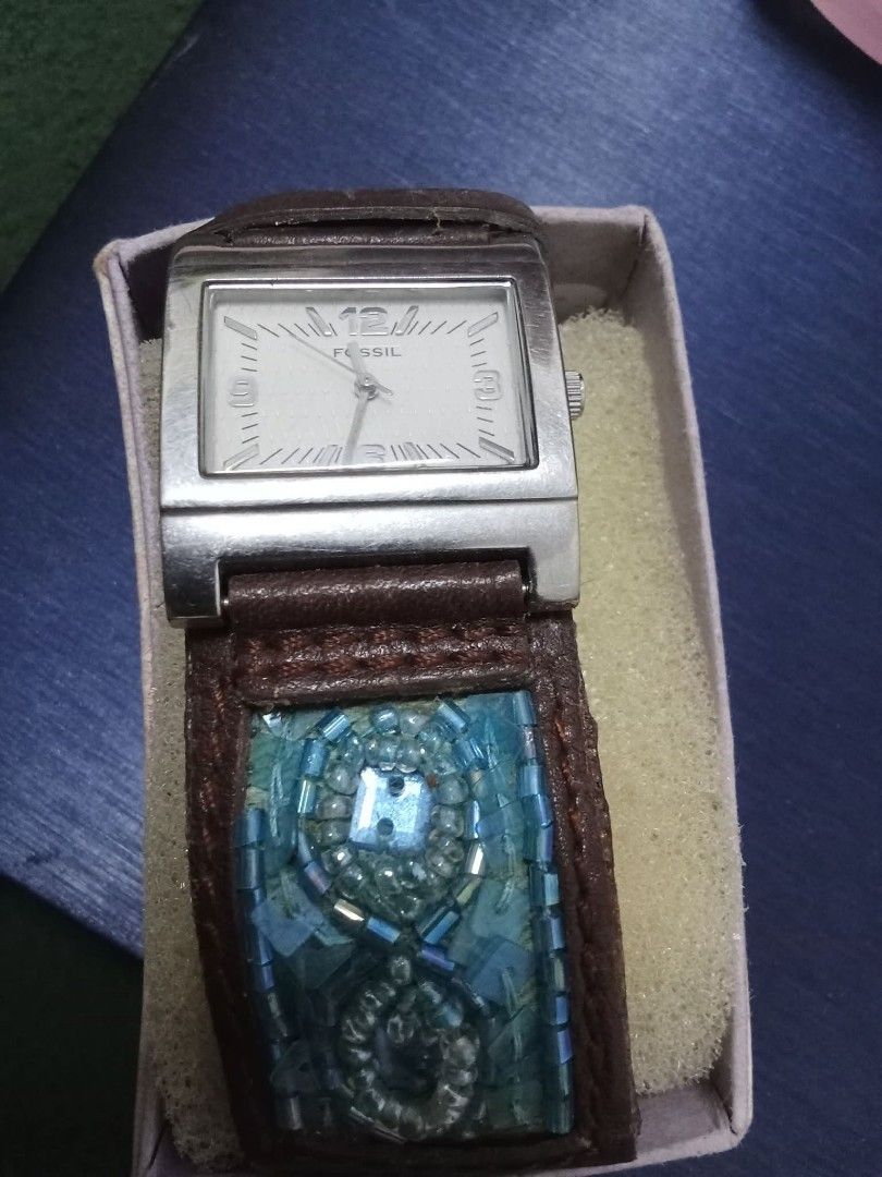 Fossil JR8832 quartz (Category: Women's Watches) located in Santa Rosa. Submitted by Sofia_Paprika (Listing ID 1465882763, Image 3). Description: - Brand: Fossil - Dial: Square white textured dial with silver numbers - Case: Silver-tone stainless steel - Strap: Brown leather cuff with intricate blue and turquoise glass beads - Inclusions: Original storage box included - Condition: Excellent, unique statement piece.