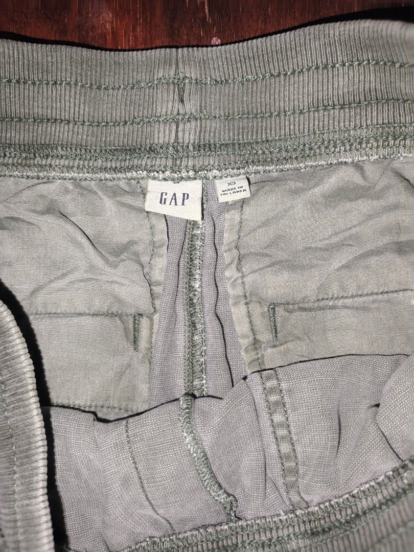 GAP Olive Green Jogger Pants Size XS (Category: Joggers) located in Manila. Submitted by esteemed_shop (Listing ID 1465896092, Image 3). Description: - Brand: Gap - Color: Olive Green - Size: XS - Material: Soft cotton blend - Origin: Made in Sri Lanka - Waistband: Elastic with drawstring tie - Pockets: Front patch pockets - Cuffs: Ribbed at the ankles - Style: Casual slip-on joggers.